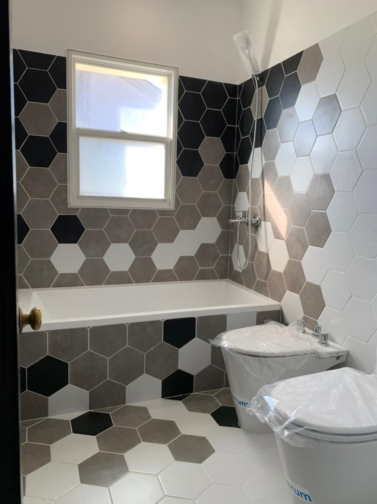 Baño moderno con azulejos hexagonales y bañera exenta — proyecto La Lomada, por Arcucci Arquitectura, en H5CM+WM